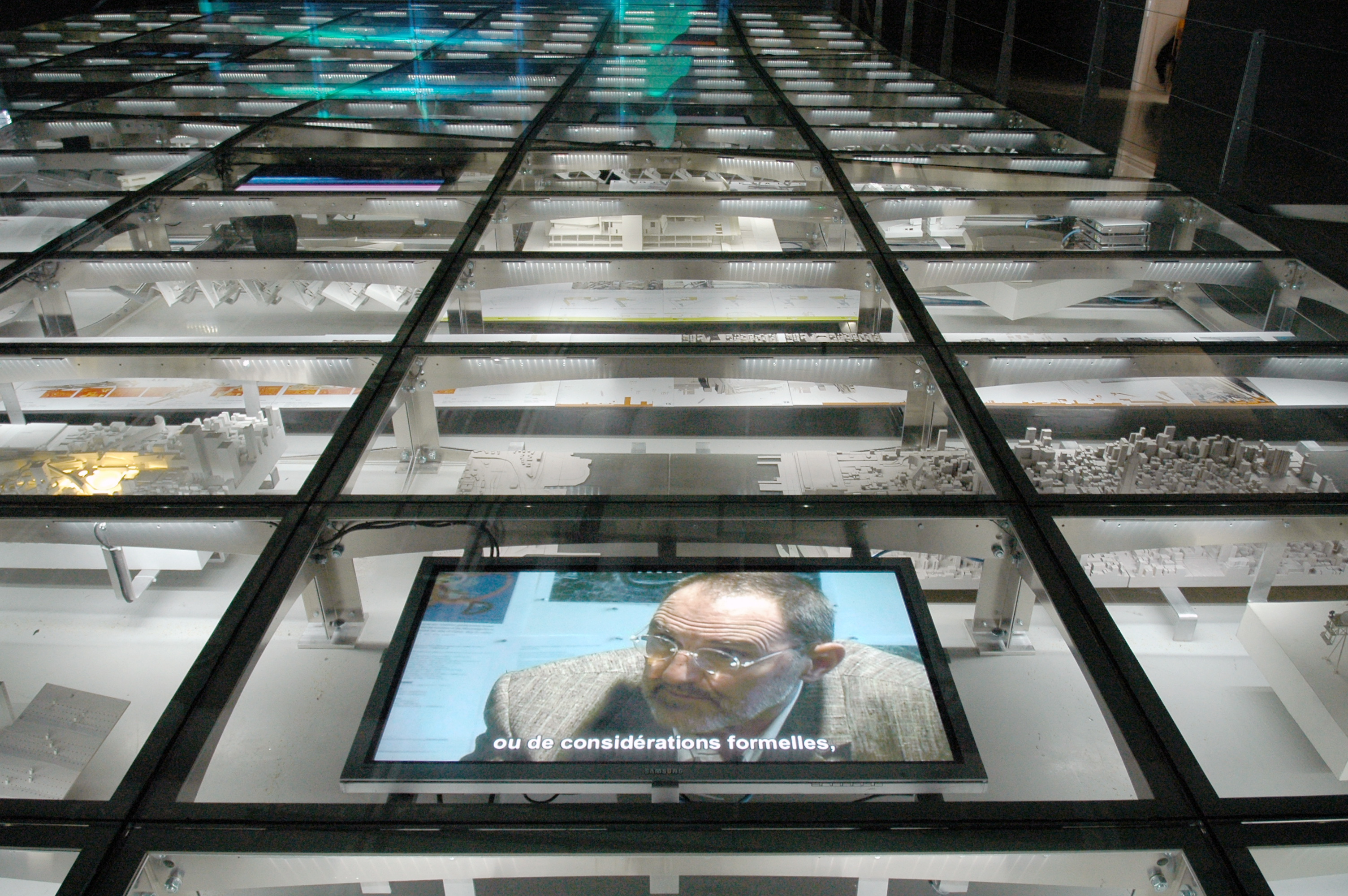 Video screens show Thom Mayne of Morphosis underneath the glass flooring.