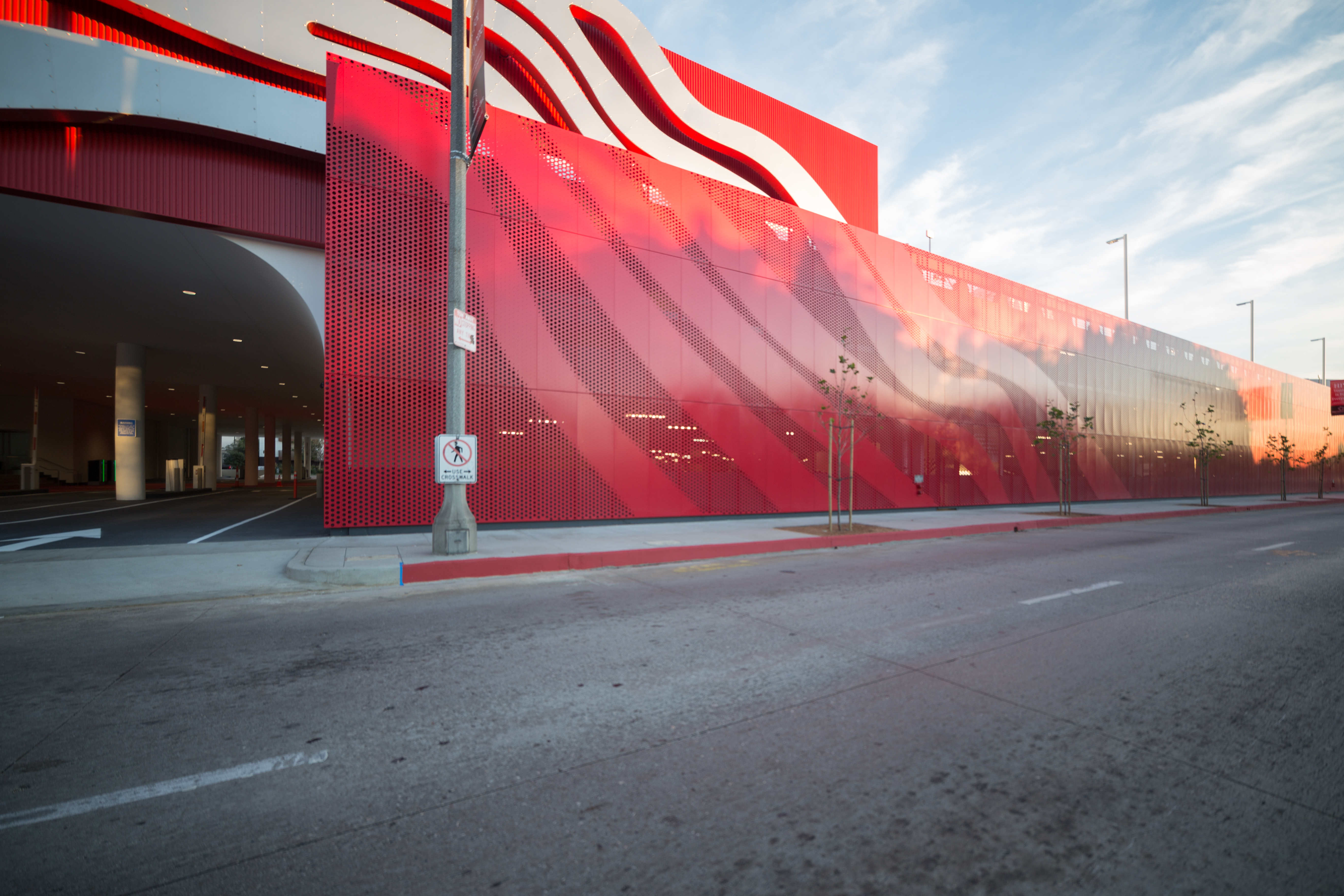 A perforated parking garage facade continues the stainless steel ribbon motif.