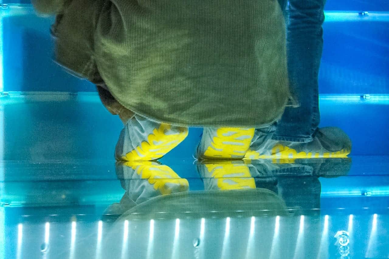 Visitors walk across the raised glass floor in custom shoe-covers.