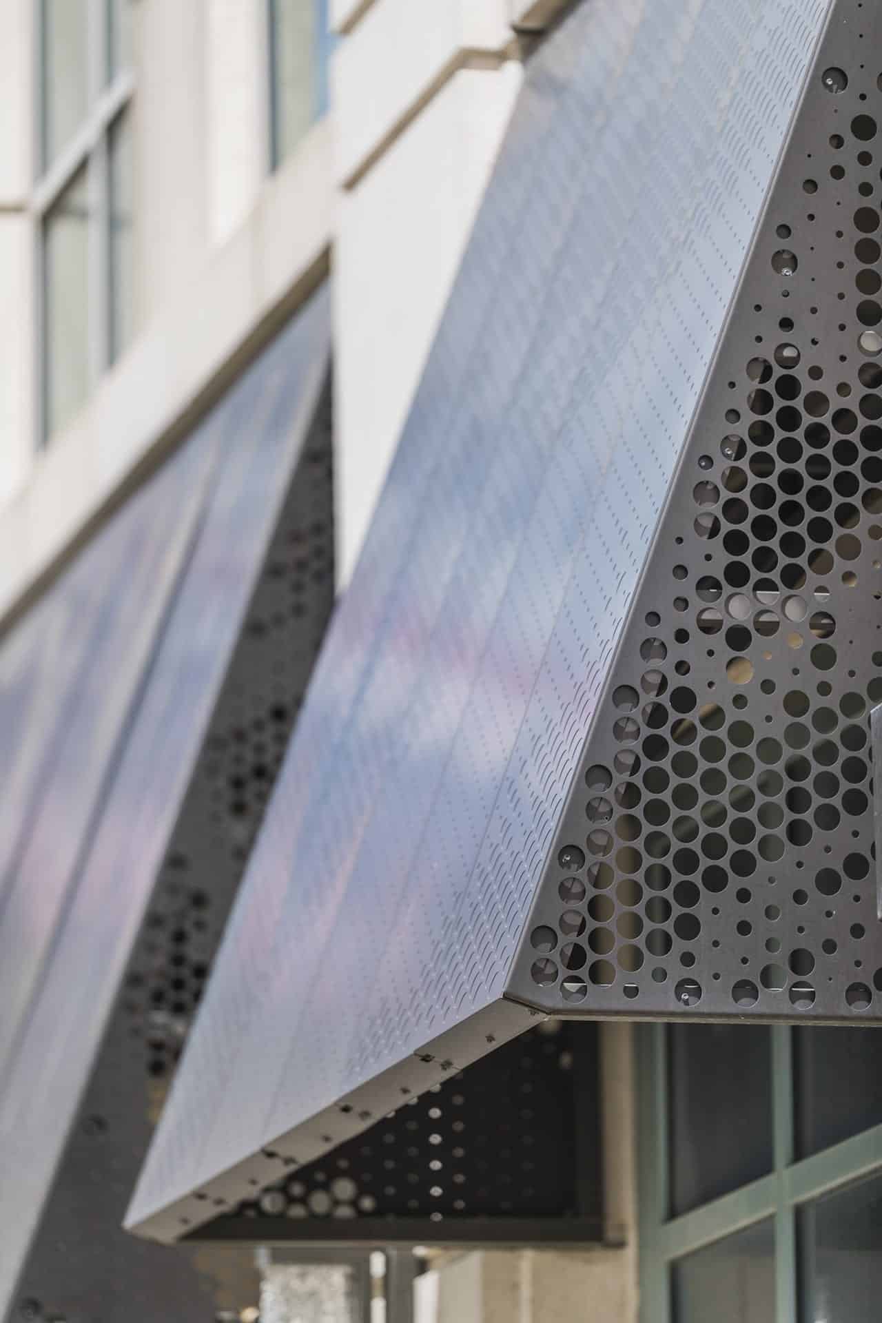 Anodized aluminum panels and structure for a series of awnings. Raised circles on the front create a pattern while still protecting from the elements.