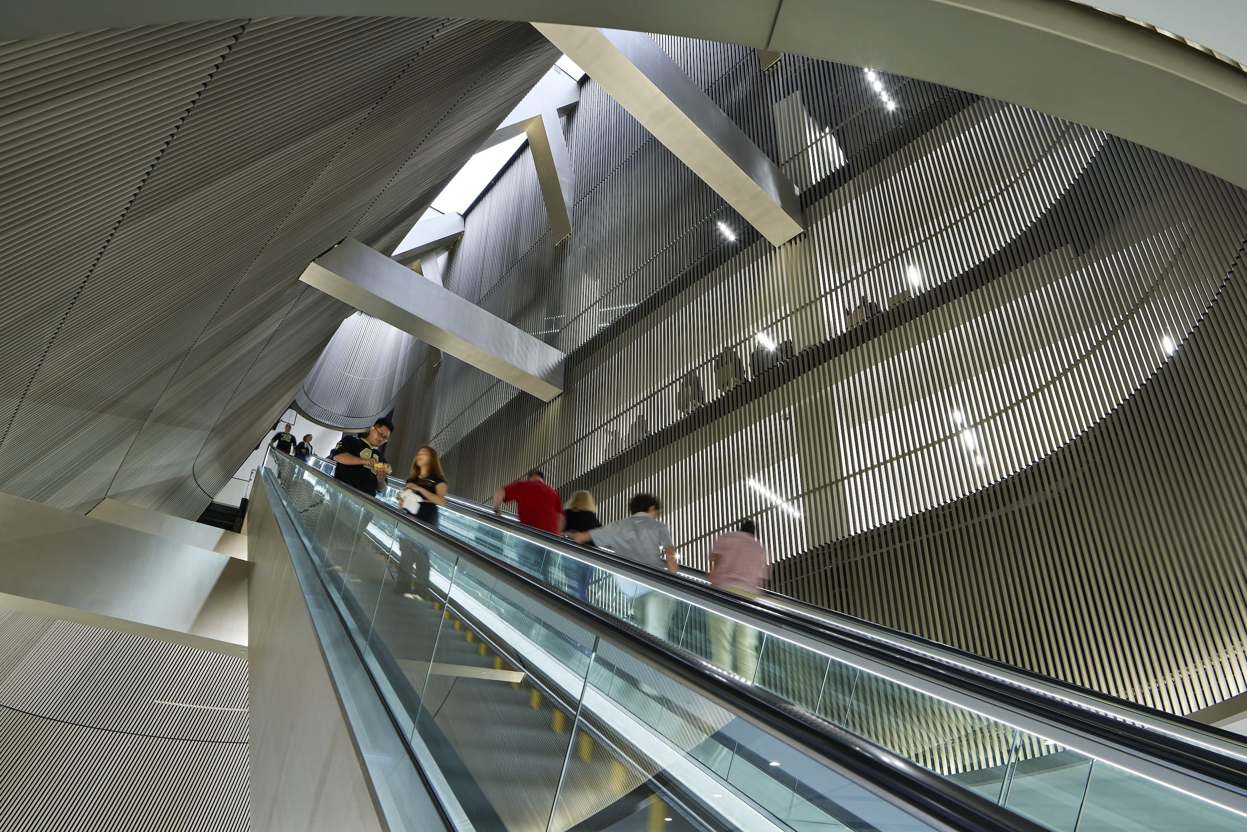 Daylight illuminates the escalator space, amplifying the glow of the gold anodized aluminum.